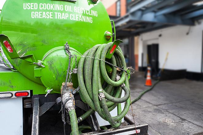 a professional plumber using a pump to empty a grease trap in Blacklick, OH